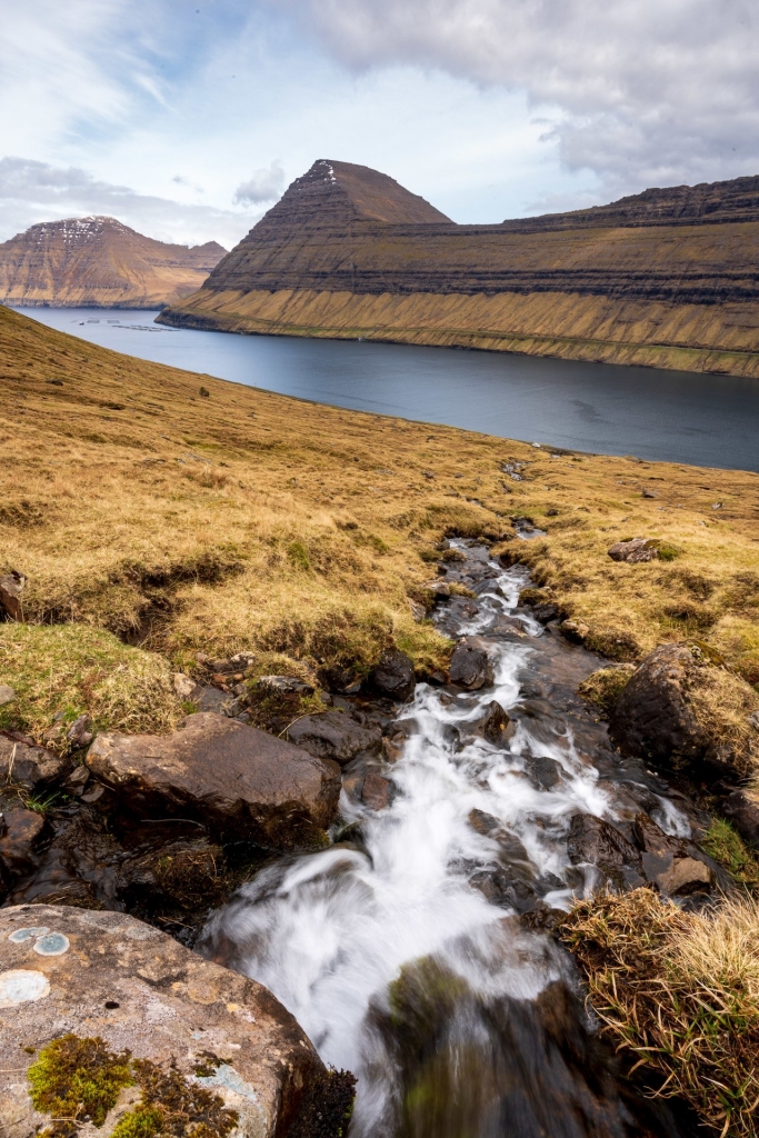 Rzeka płynąca zboczem na wyspie Borðoy z wyspą Viðoy w tle